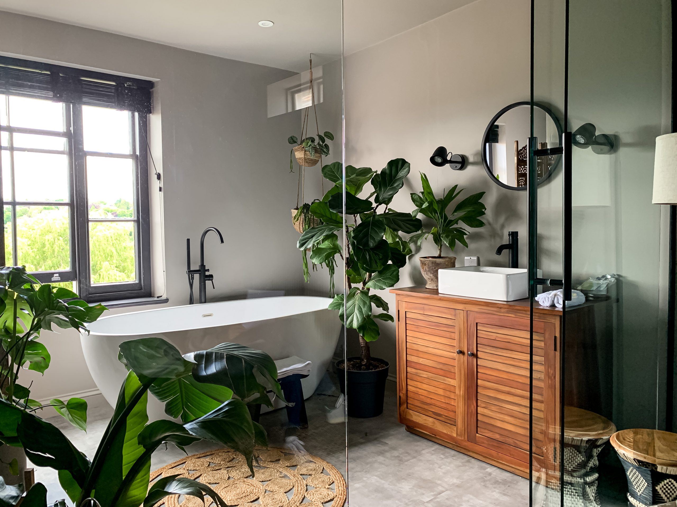 Charming cozy bathroom view. Bath tube by the window. taking bath at home or in a hotel. Charming cozy indonesian style. Bathroom view. Home Plant in room. High quality photo