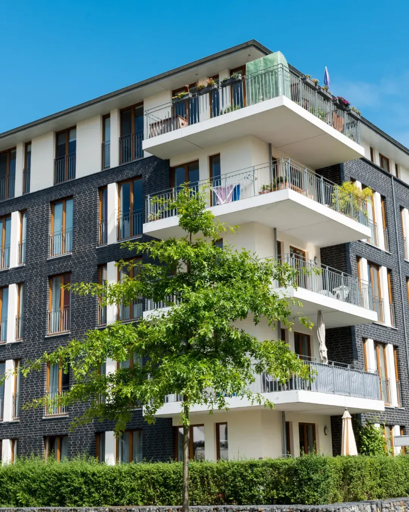Contemporary multi-unit building with dark brick exterior, spacious balconies, and landscaped surrounds