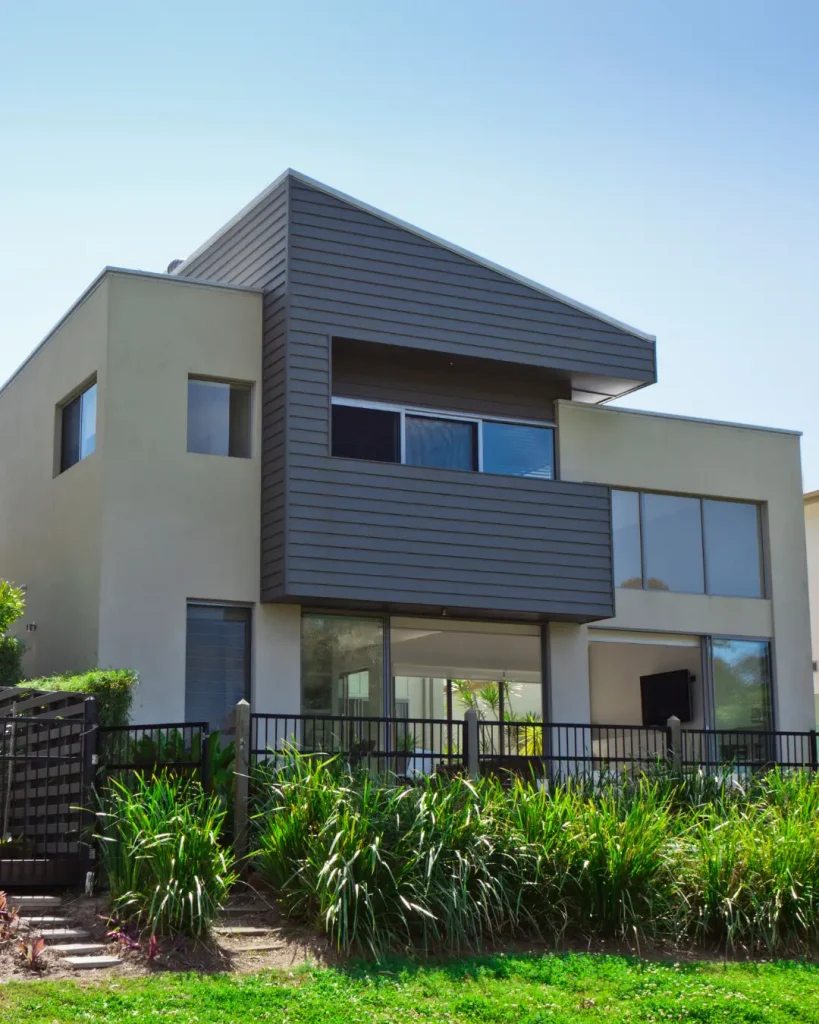 Modern sloped-roof home with clean lines, large windows, and lush native landscaping