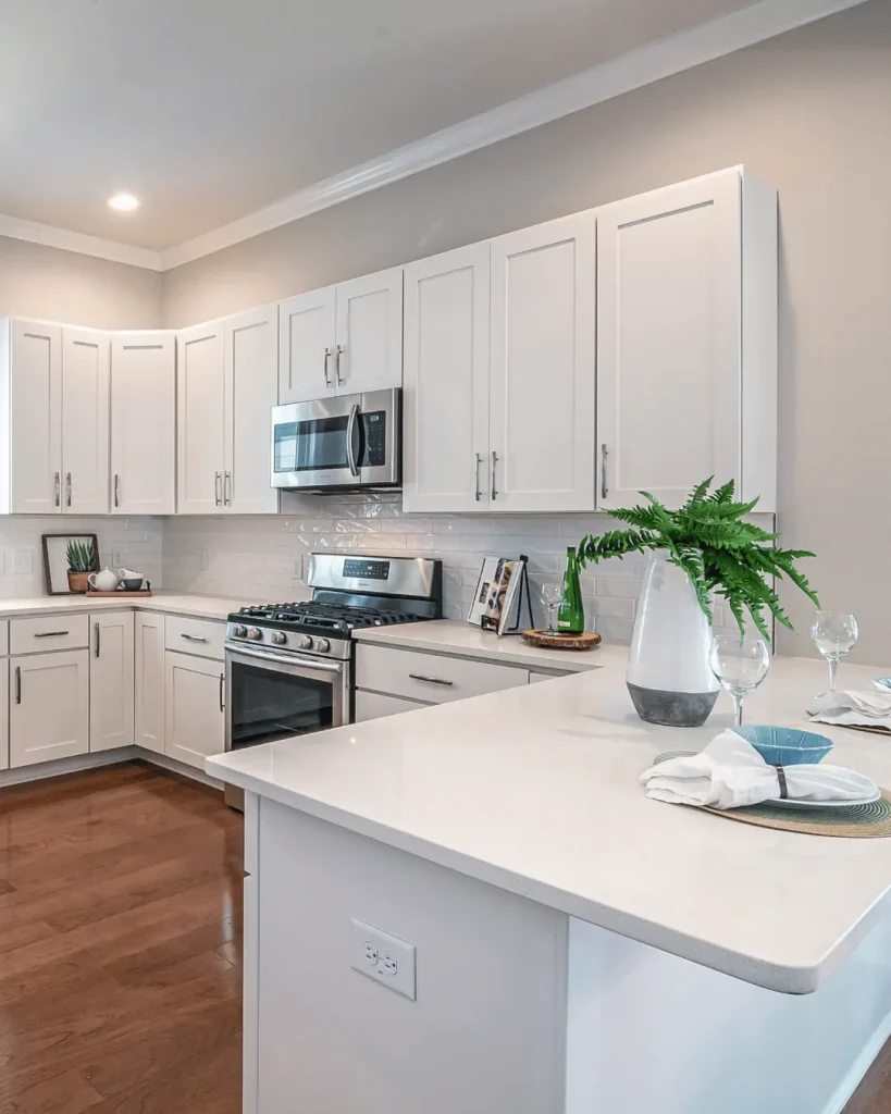 Bright white corner kitchen with shaker cabinetry, quartz countertops and stainless steel appliances.