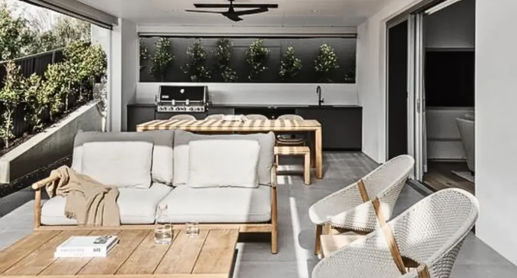 Stylish outdoor dining and lounge area with a built-in BBQ, timber furniture, and feature wall with vertical plants.