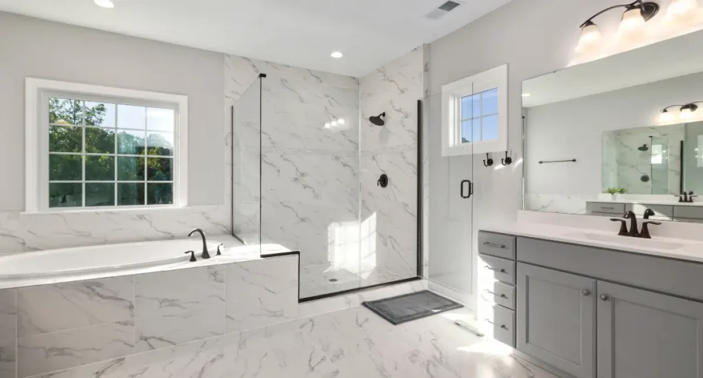 Renovated bathroom with marble-look tiles, walk-in glass shower, and built-in bathtub.