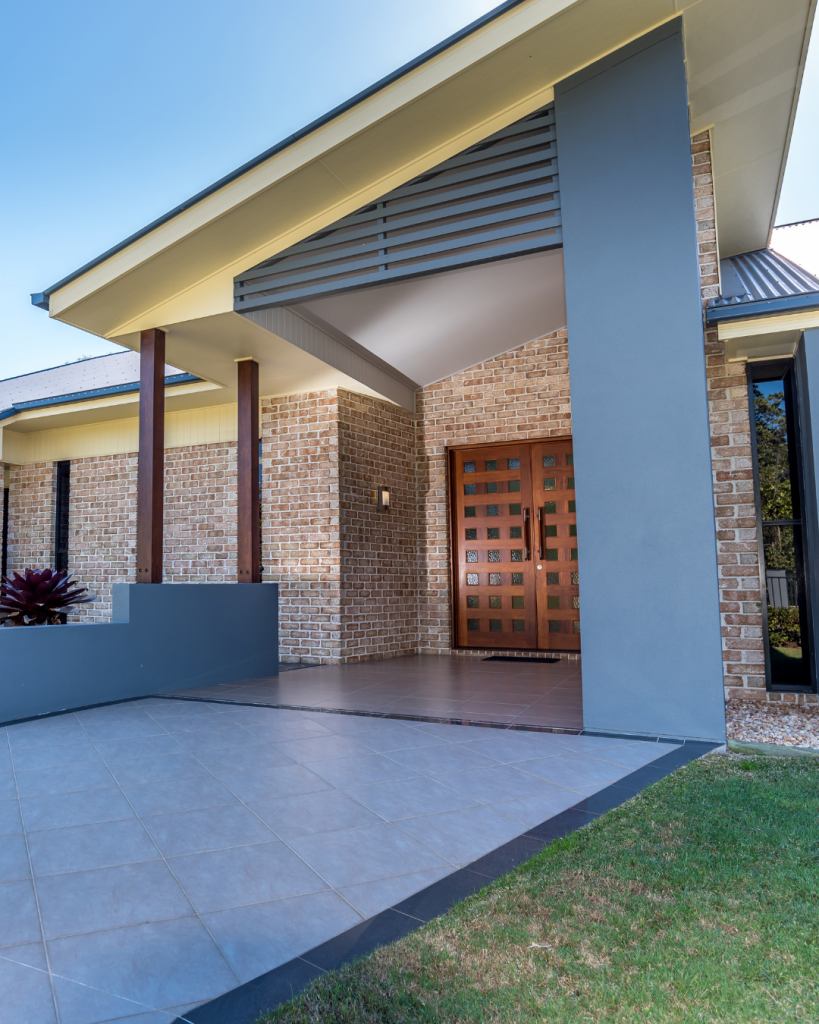 Custom-built Melbourne home with brick facade, timber feature door, and modern tiled entryway.