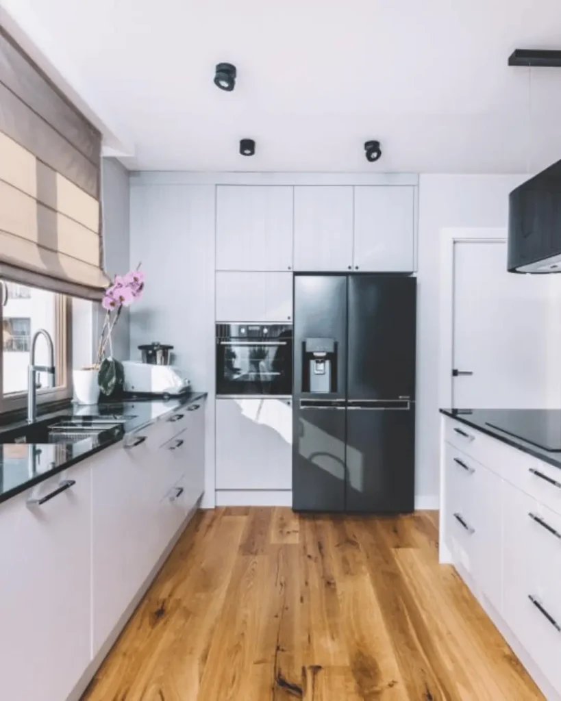 Sleek kitchen design with timber flooring, matte black appliances, and white cabinetry – Radevo Living