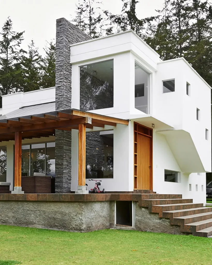 Modern knockdown rebuild with pitched roof, full-width timber garage, and large upper balcony.
