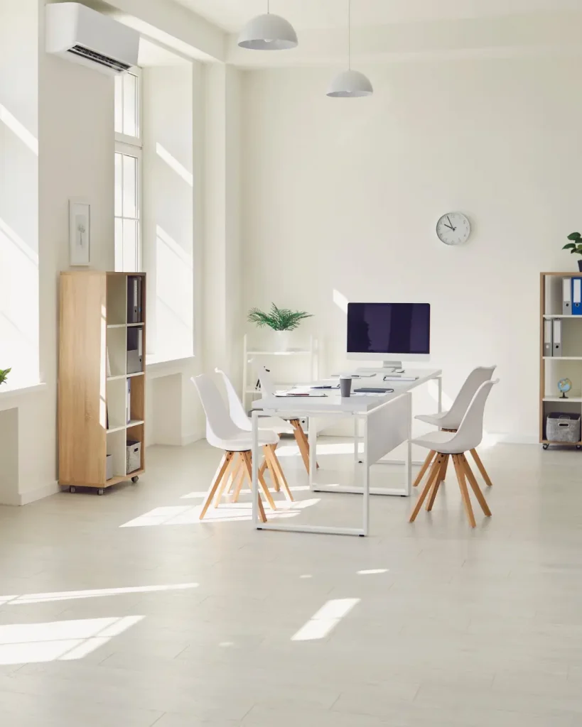 Bright and minimal home office space with white walls, modern furniture, and natural light.