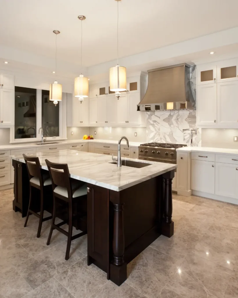 Traditional luxury kitchen with marble countertops, a large island, pendant lighting, and stainless-steel range hood.