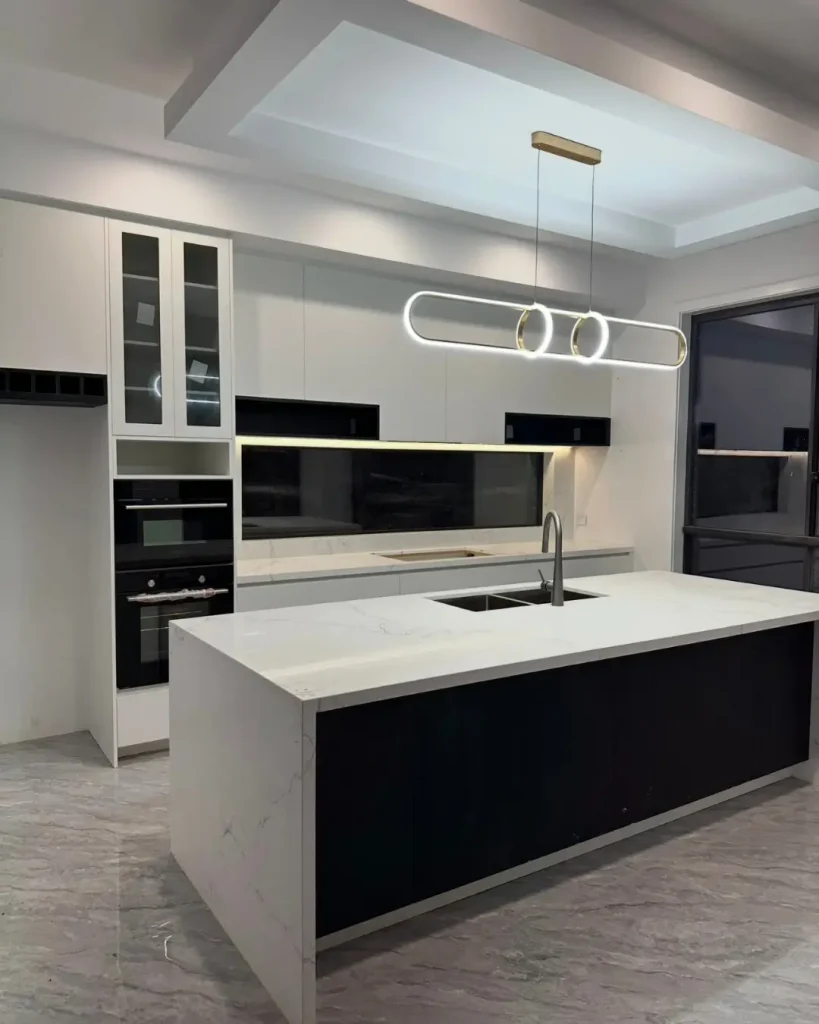 Contemporary kitchen with island bench, integrated appliances, pendant lighting, and marble finishes.