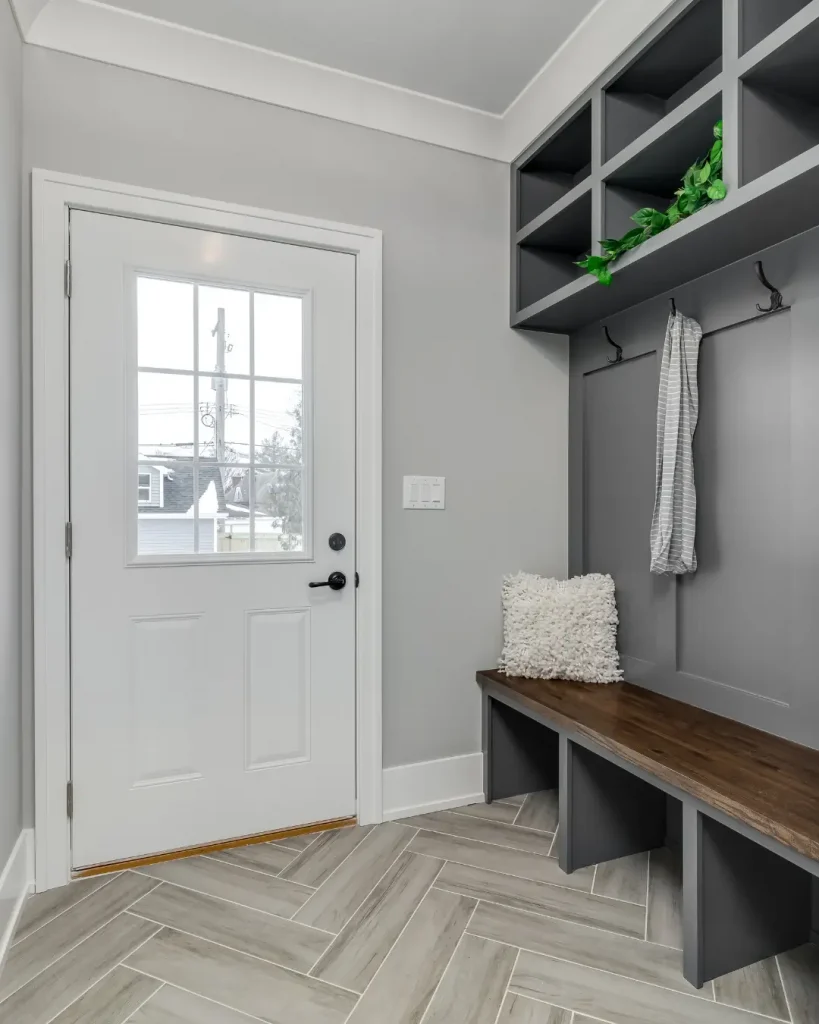 Modern entryway with built-in mudroom bench, open cubby storage, and wall hooks.