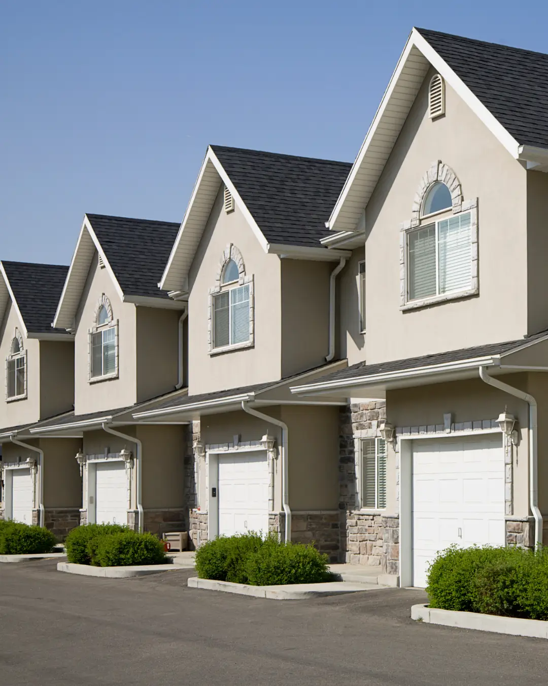 Row of beige dual occupancy homes with garages in a suburban streetscape