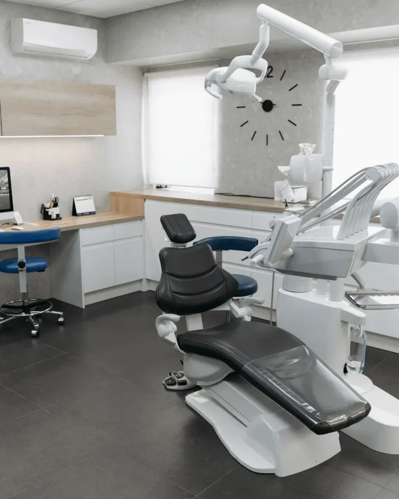 Modern dental clinic interior with treatment chair, overhead light, and clean cabinetry.
