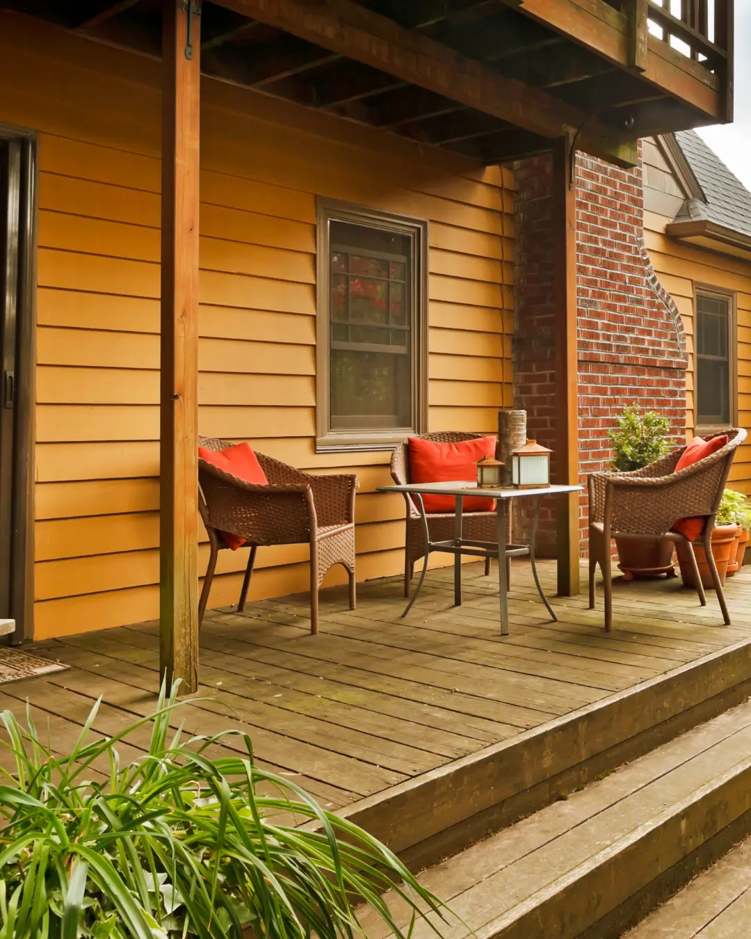 Timber deck with pergola featuring outdoor seating and brick accents on a renovated home exterior.