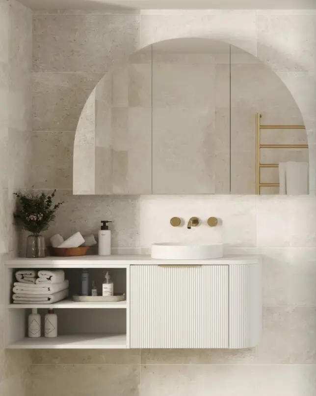 Curved white vanity with integrated storage and arched mirror, set against soft neutral tiles