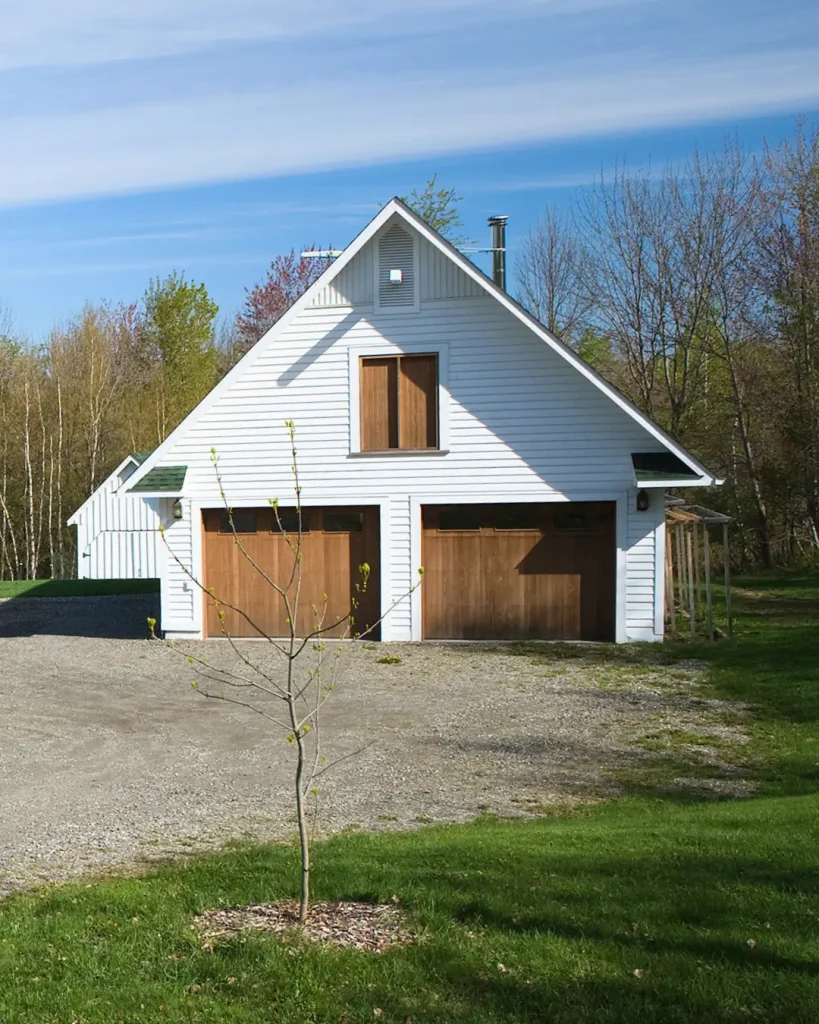 White barn-style home with timber garage doors and pitched roof.