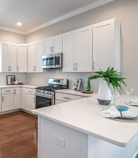 Bright white corner kitchen with shaker cabinetry, quartz countertops and stainless steel appliances.