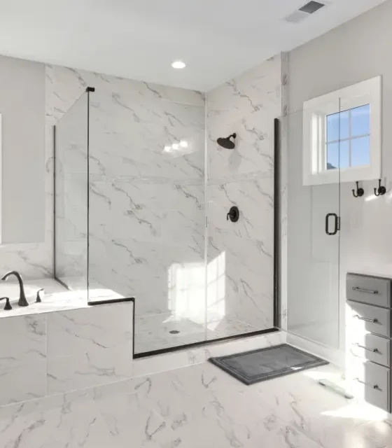 Renovated bathroom with marble-look tiles, walk-in glass shower, and built-in bathtub.
