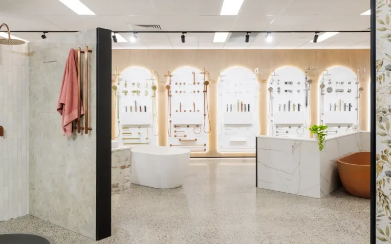 Modern bathroom showroom with wall-mounted shower and tapware displays, freestanding bathtubs, and elegant lighting.