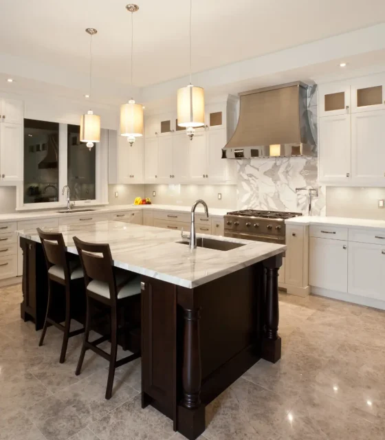 Traditional luxury kitchen with marble countertops, a large island, pendant lighting, and stainless-steel range hood.