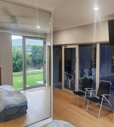 Indoor space with large glass doors opening to a green backyard and outdoor seating area.