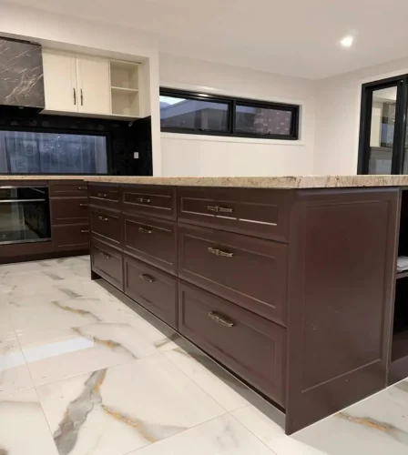 Kitchen renovation with deep brown shaker cabinetry, marble-look flooring, and stone benchtop