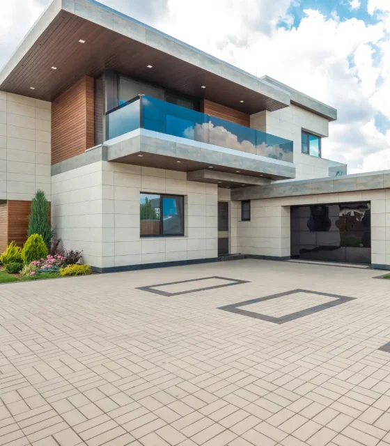 Modern double-storey home with sleek lines, glass balcony, and tiled driveway in Melbourne.