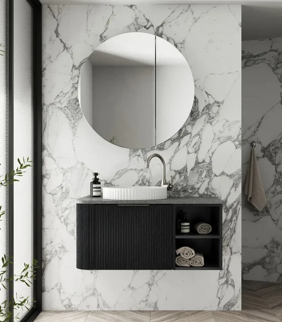 Luxury black fluted vanity with round mirror and textured stone benchtop against full-height marble wall