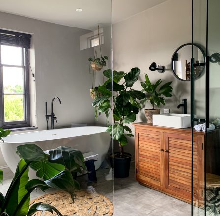 Charming cozy bathroom view. Bath tube by the window. taking bath at home or in a hotel. Charming cozy indonesian style. Bathroom view. Home Plant in room. High quality photo