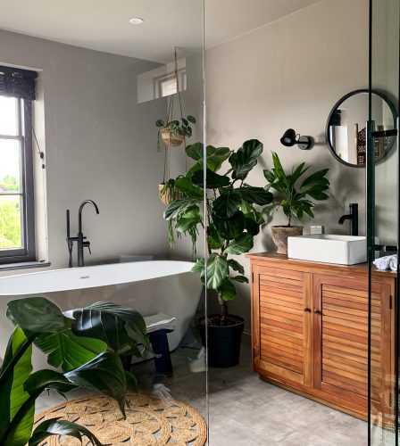Charming cozy bathroom view. Bath tube by the window. taking bath at home or in a hotel. Charming cozy indonesian style. Bathroom view. Home Plant in room. High quality photo